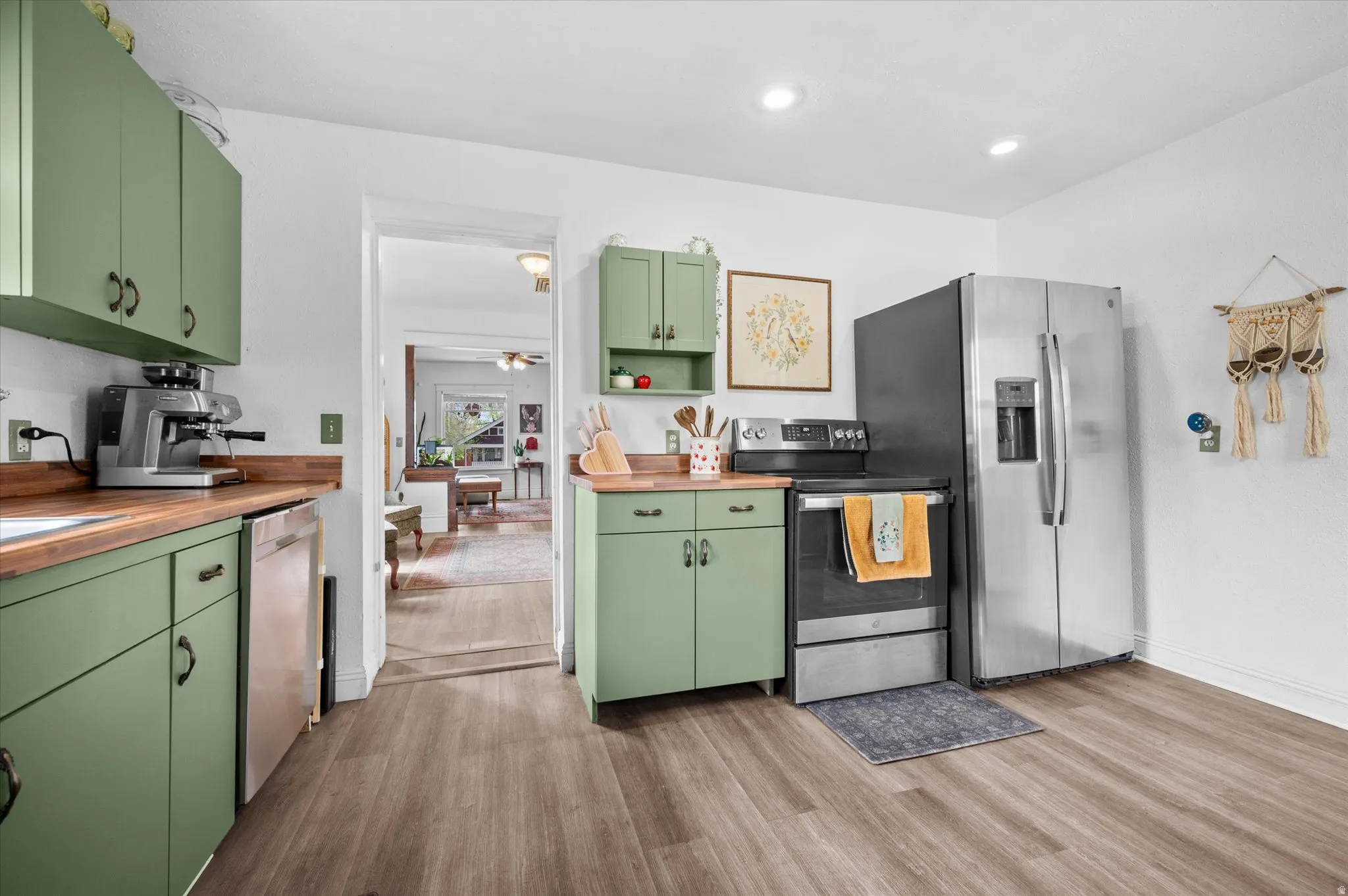 Kitchen featuring green cabinetry, stainless steel appliances, dark wood-type flooring, butcher block counters, and open shelves