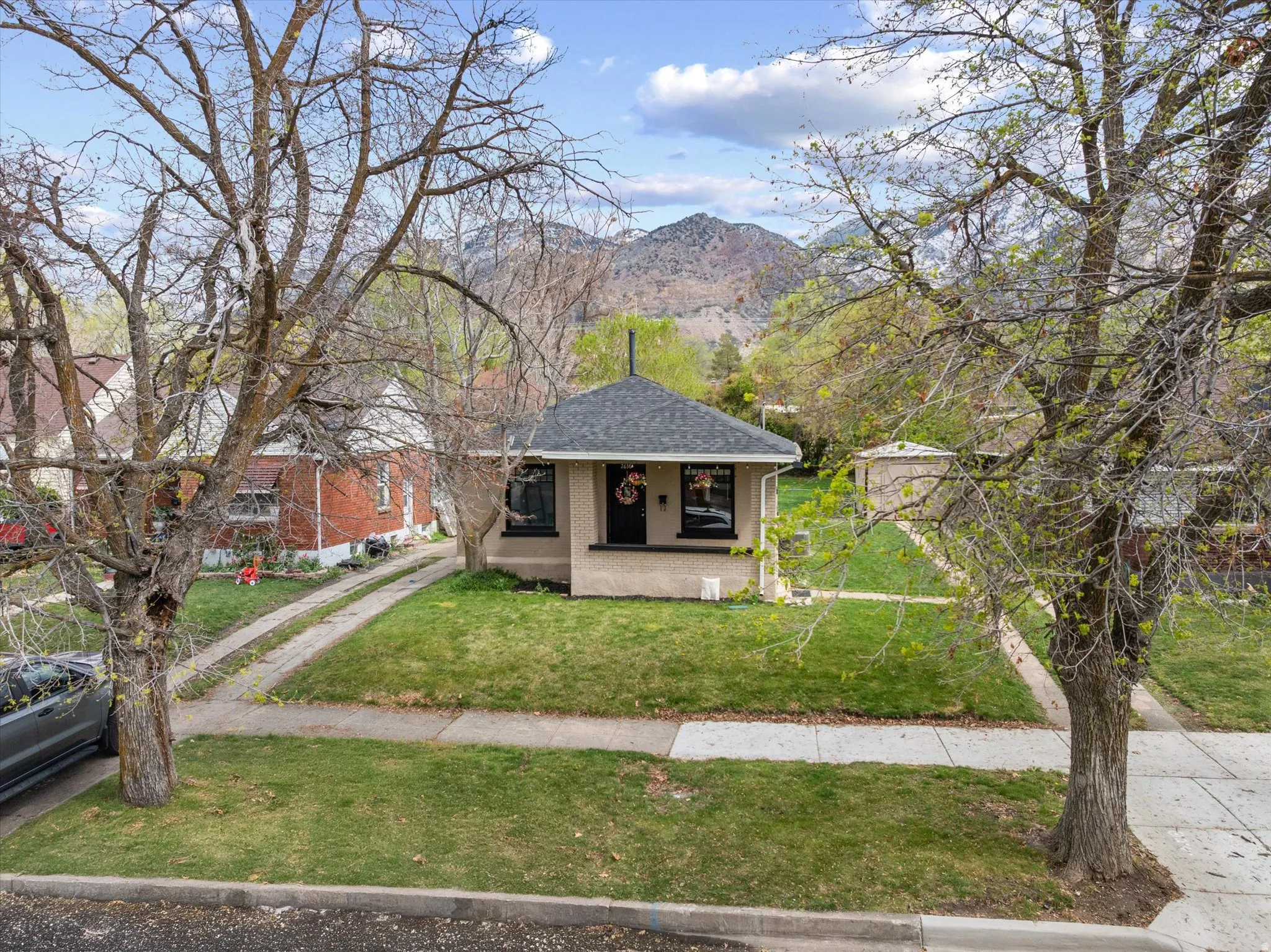 View of front of house featuring covered porch, a front lawn, roof with shingles, and a mountain view