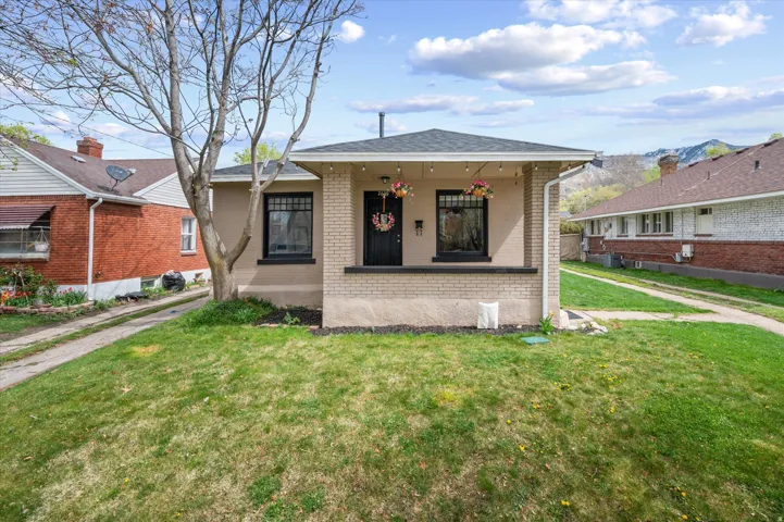 Bungalow-style home featuring a front lawn, brick siding, a porch, and a shingled roof