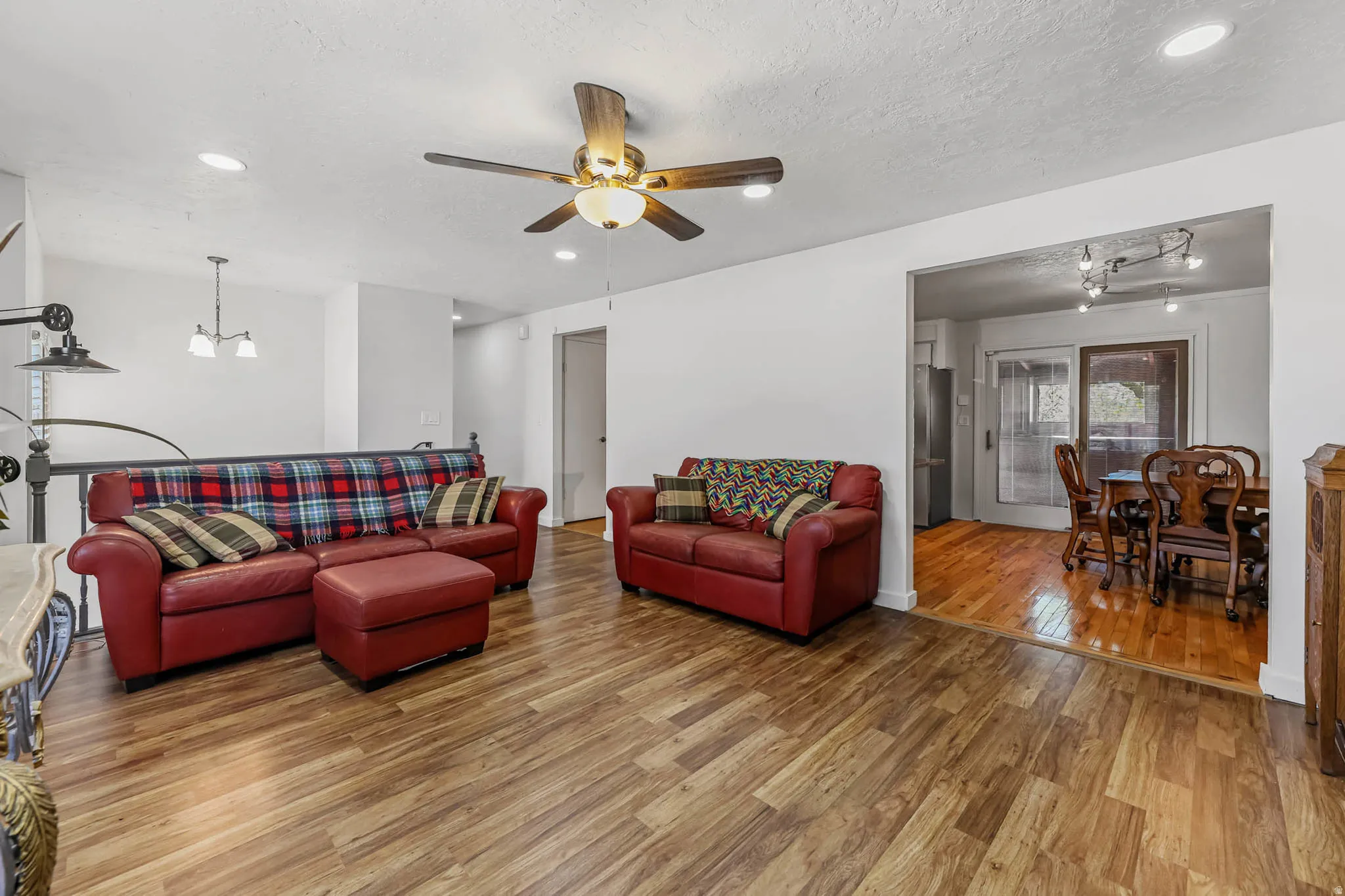 Living room featuring hanging lights, wood finished floors, a textured ceiling, and ceiling fan