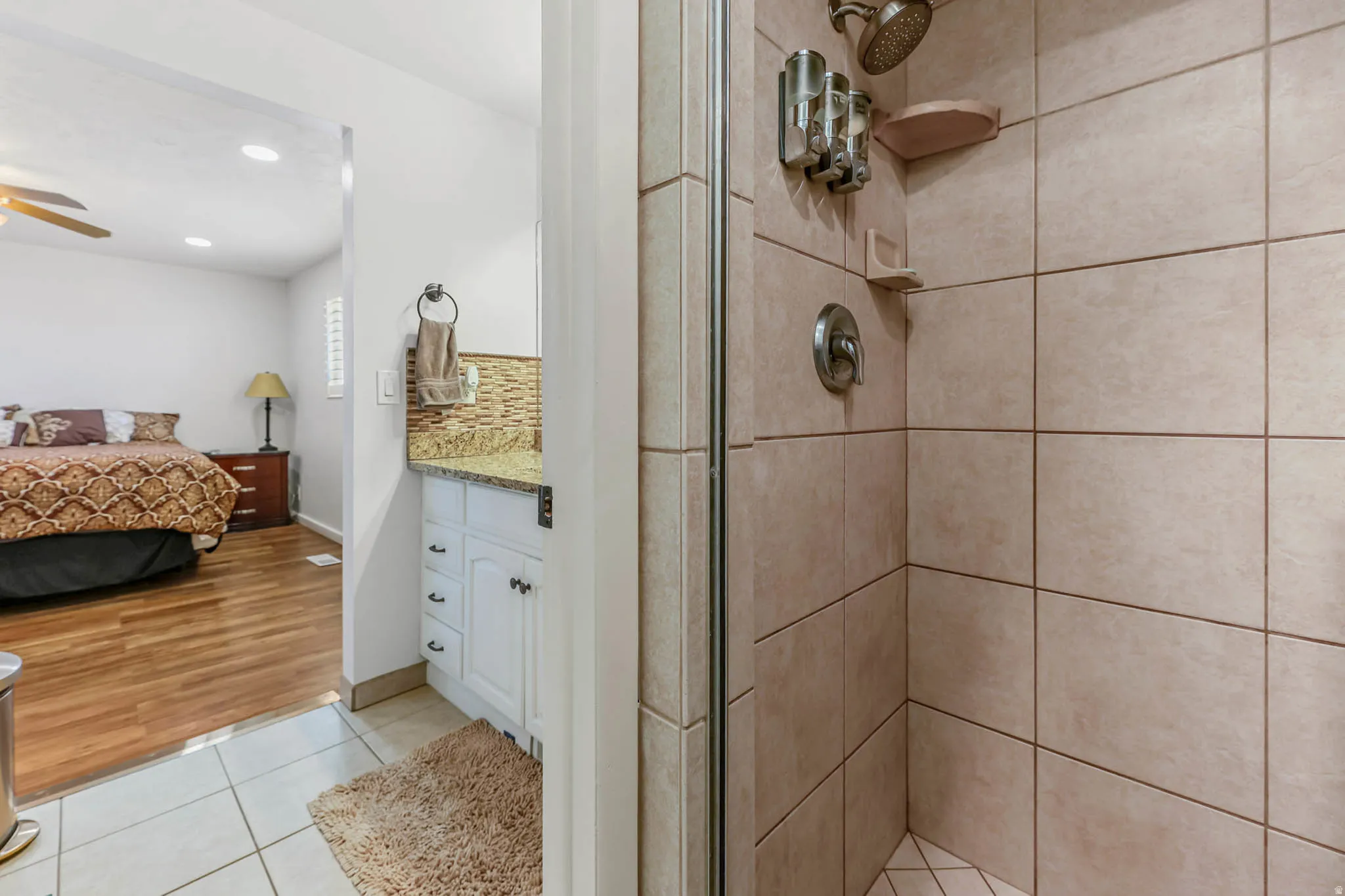 Bathroom featuring ensuite bathroom, vanity, a shower stall, light tile patterned flooring, and ceiling fan