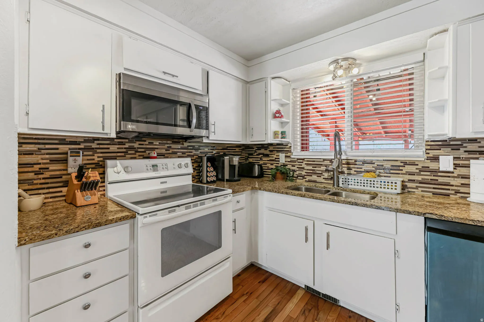 Kitchen featuring electric range, open shelves, white cabinetry, stainless steel microwave, and ornamental molding