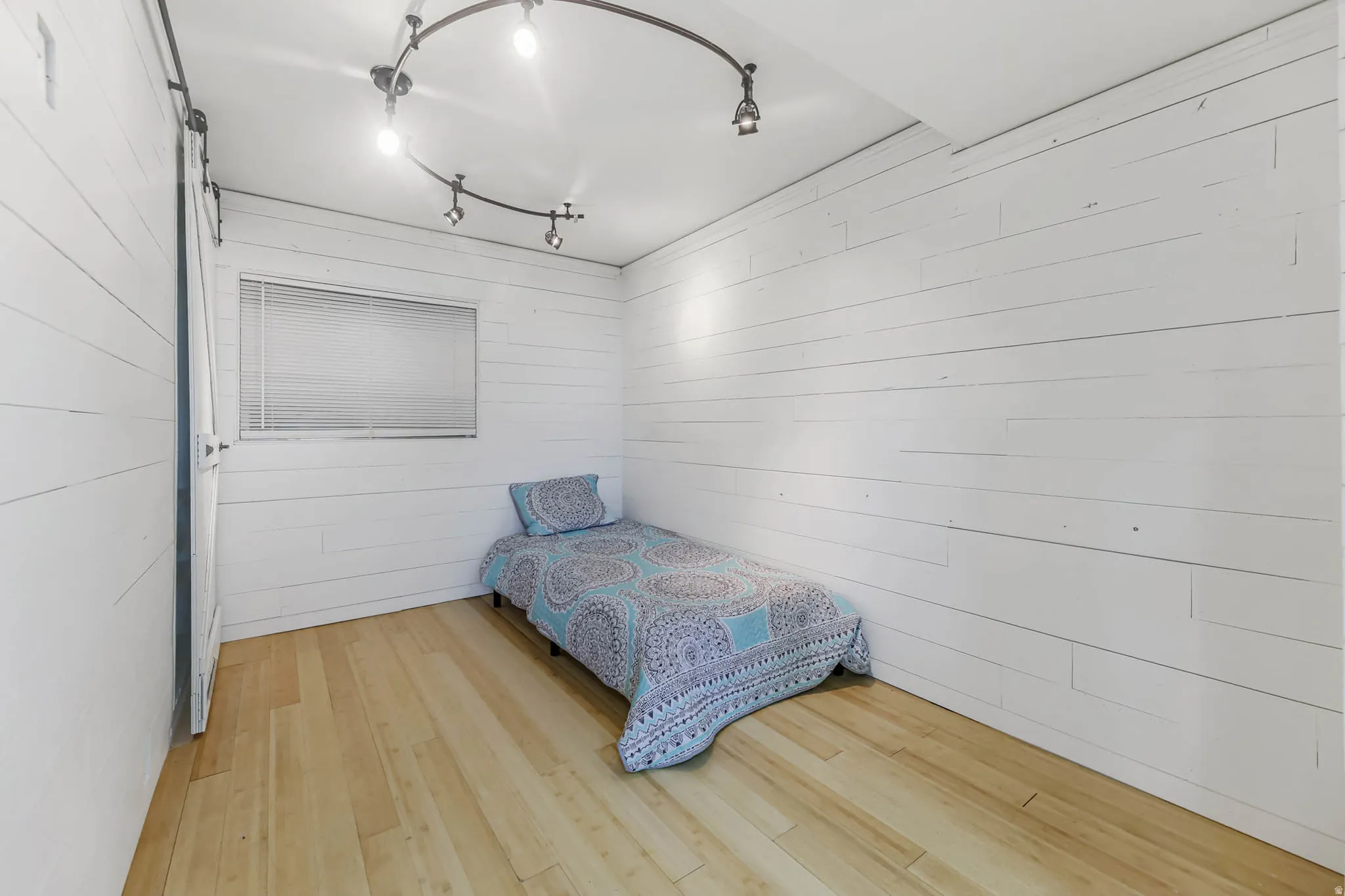 Bedroom with wood walls and light wood-type flooring