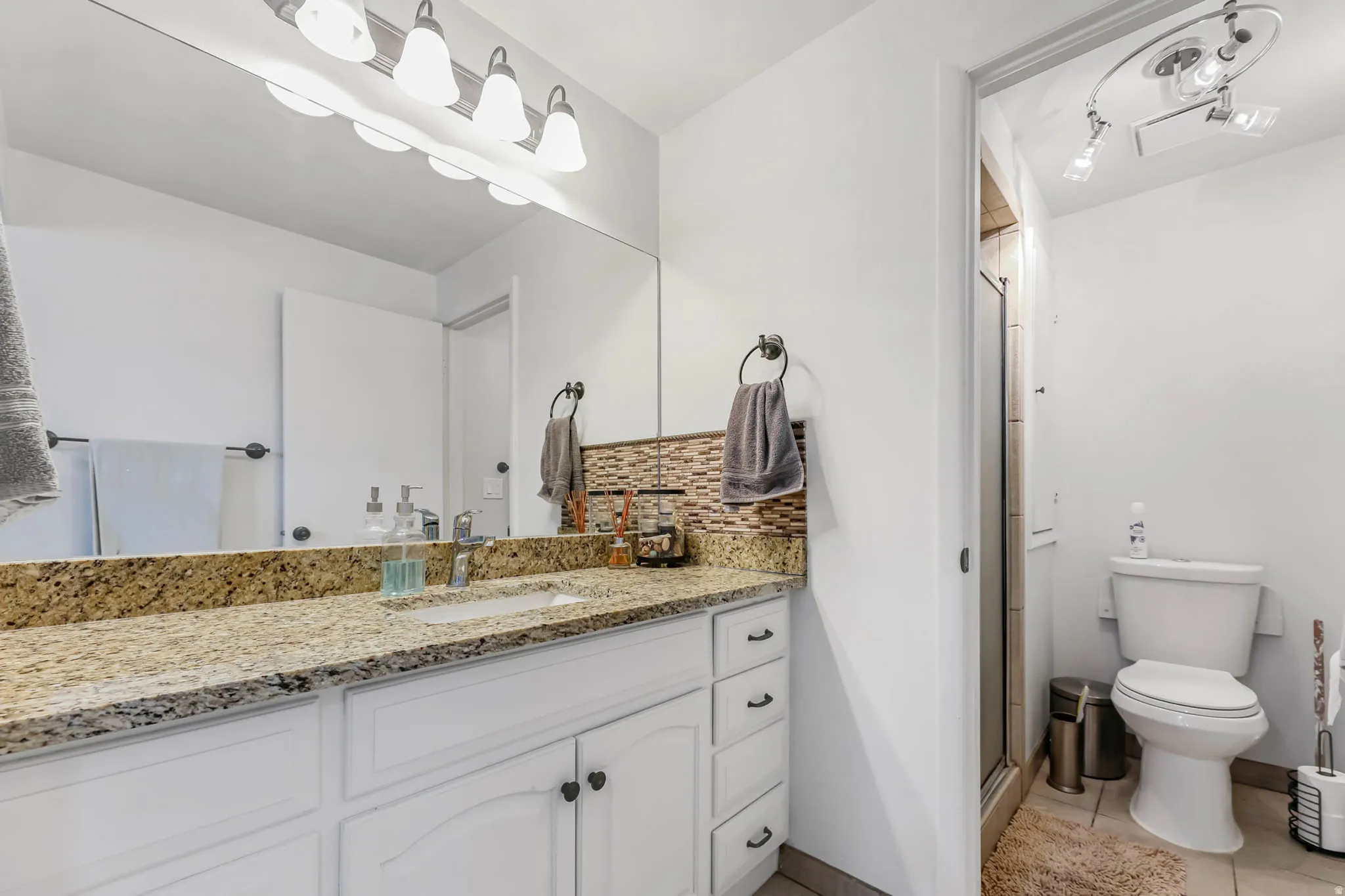 Full bath with backsplash, a stall shower, vanity, and light tile patterned flooring