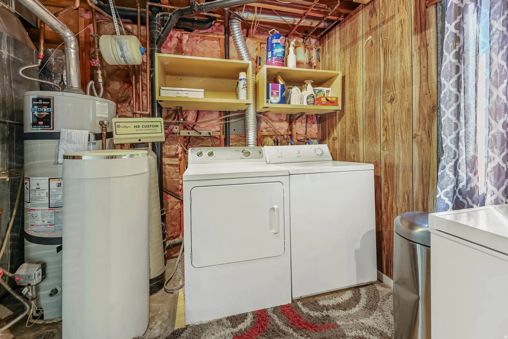 Laundry area with secured water heater, washing machine and clothes dryer, and wood walls
