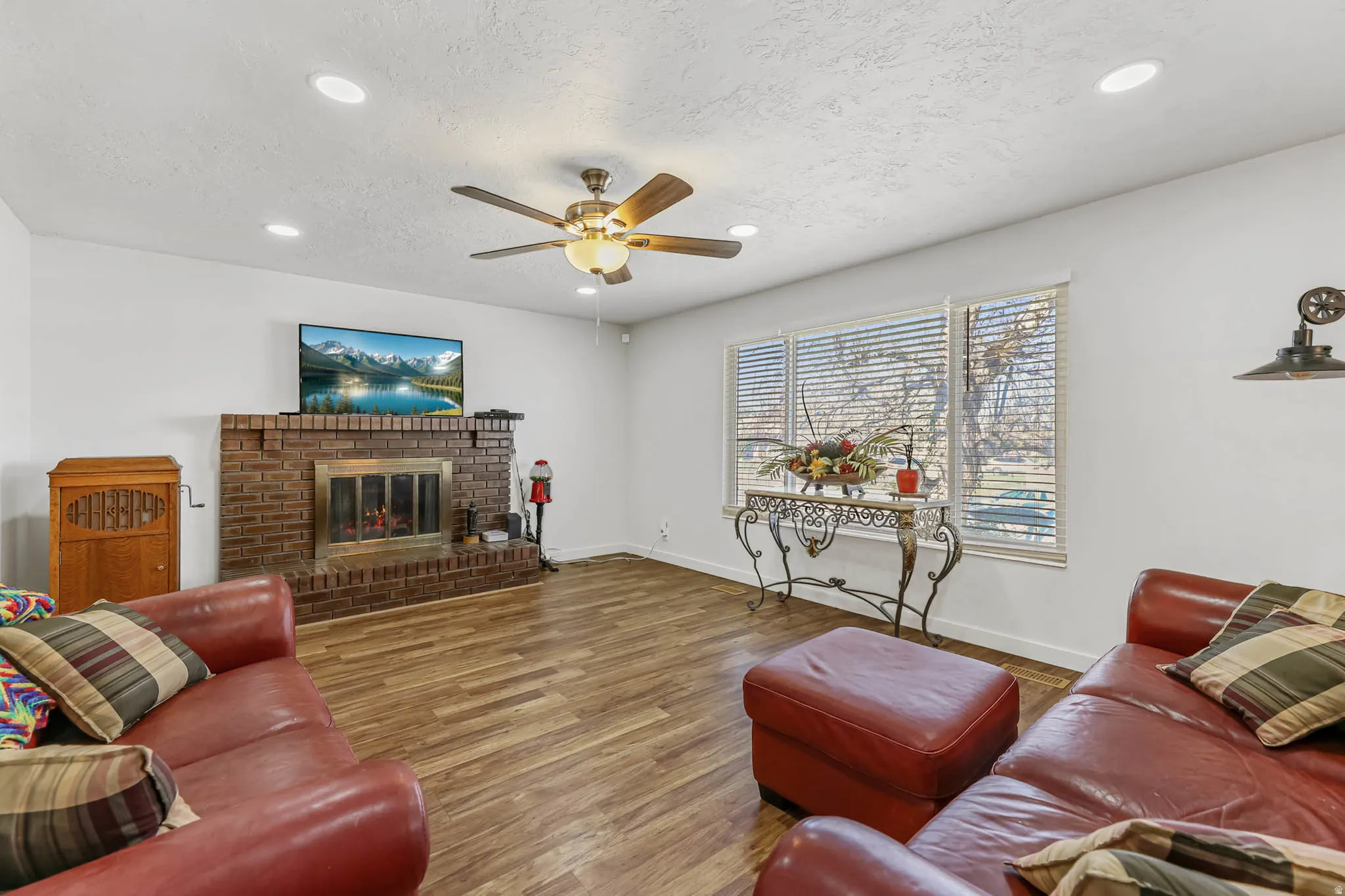 Living room featuring wood finished floors, ceiling fan, recessed lighting, a textured ceiling, and a fireplace