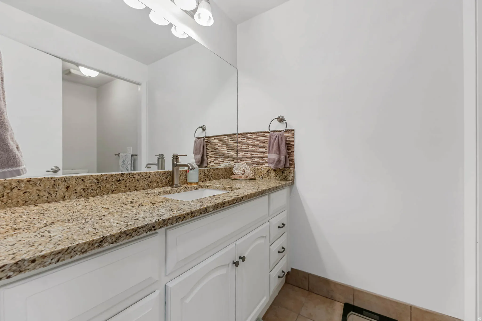 Bathroom with vanity, light tile patterned flooring, and decorative backsplash