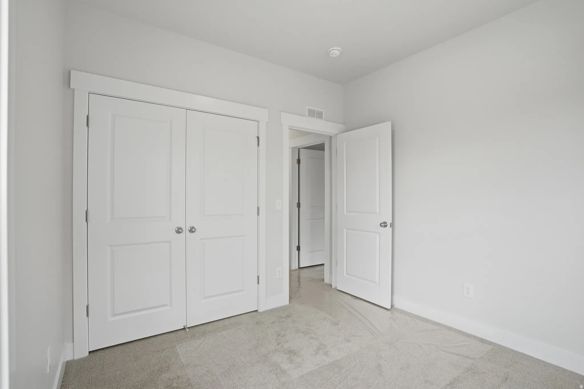 Unfurnished bedroom featuring light carpet and a closet