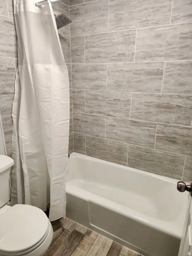 Full bathroom featuring wood tiled floors and shower / tub combo with curtain