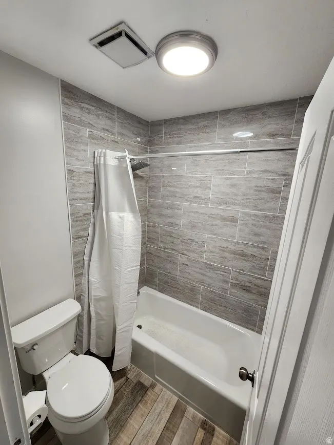 Full bath with shower / bath combination with curtain and wood tiled floors