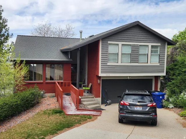 View of front of home with driveway, a garage, and a shingled roof