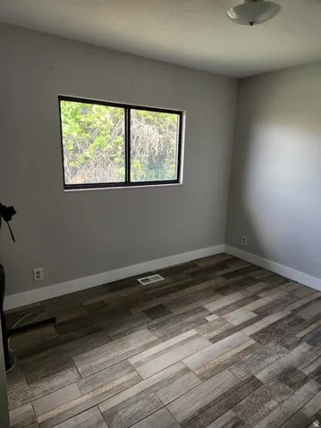 Unfurnished room with healthy amount of natural light and wood finished floors