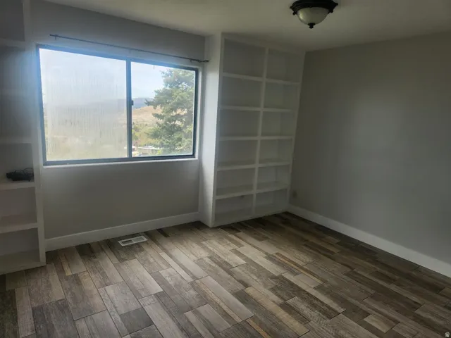 Unfurnished bedroom with wood finish floors and baseboards