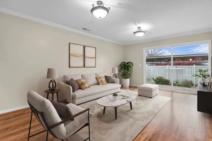 Living area with ornamental molding and light wood-style flooring