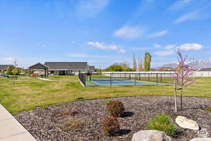 Expansive green space featuring a tennis court, covered picnic area, and distant mountain backdrop