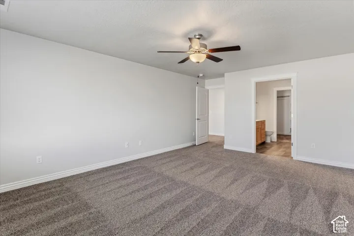 Unfurnished bedroom with ensuite bath, a ceiling fan, carpet floors, and a textured ceiling