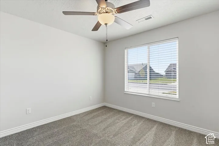 Unfurnished room with ceiling fan, a textured ceiling, and carpet floors