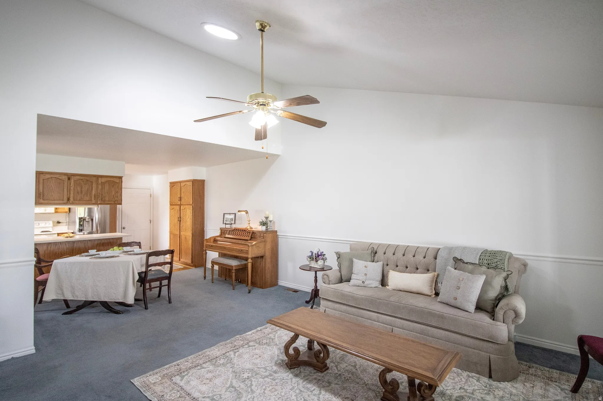 Living room featuring vaulted ceiling, skylight and ceiling fan