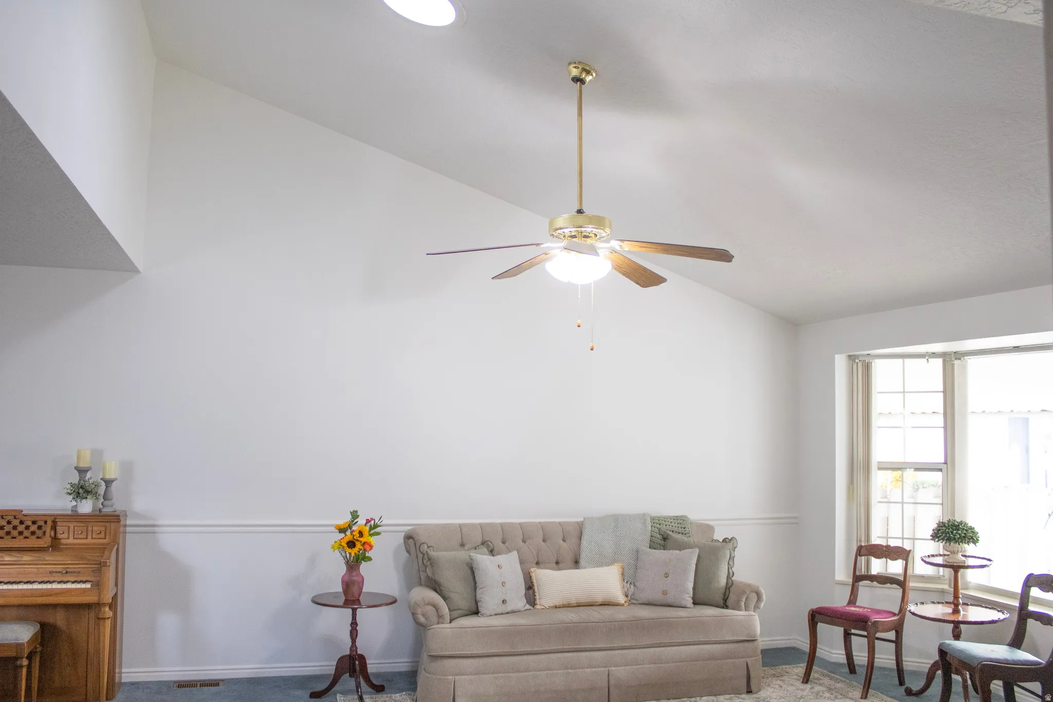 Living room featuring vaulted ceiling, skylight, bay window and ceiling fan