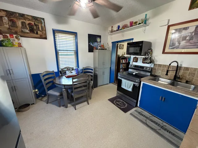 Kitchen featuring stainless steel electric range, a textured ceiling, ceiling fan, black microwave, and blue cabinetry