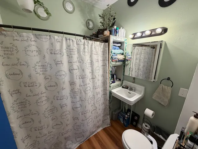 Full bath with wood finished floors and a shower with shower curtain