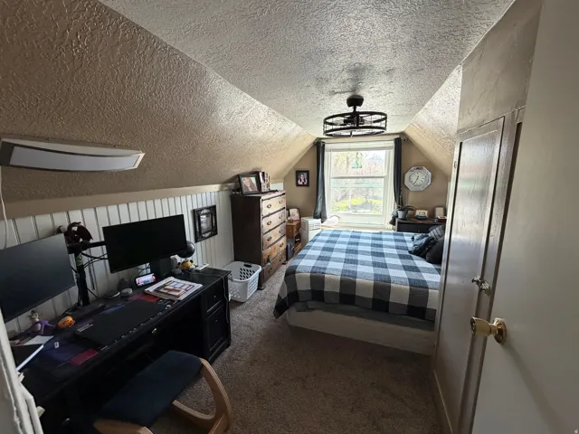 Bedroom with dark carpet and a textured ceiling