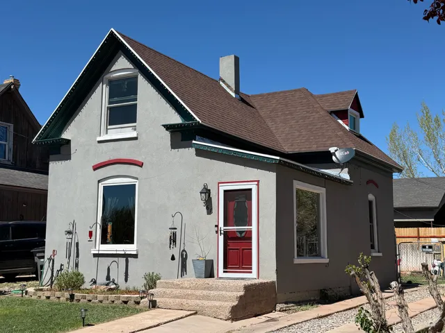 View of front of home featuring a shingled roof, stucco siding, and a chimney