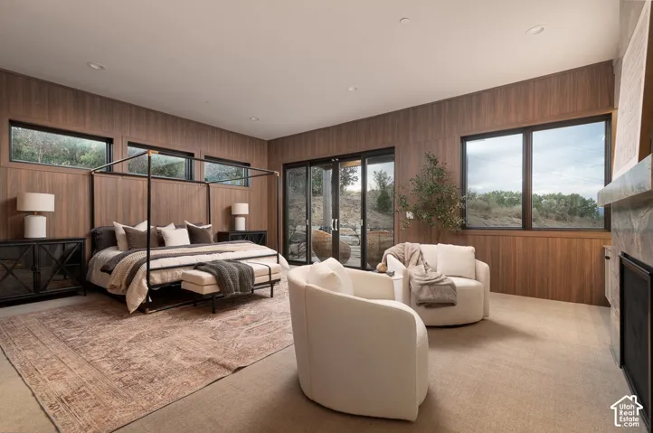 Bedroom featuring wood walls, access to outside, light colored carpet, and a fireplace
