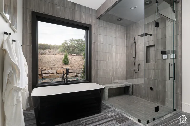 Bathroom with a freestanding bath, a shower stall, and tile patterned flooring