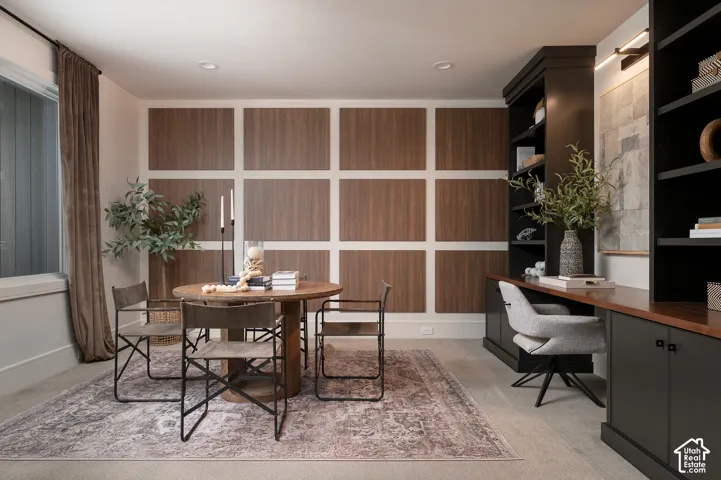 Home office featuring built in desk and light colored carpet