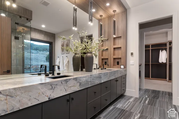Full bath with double vanity, recessed lighting, a stall shower, and a walk in closet