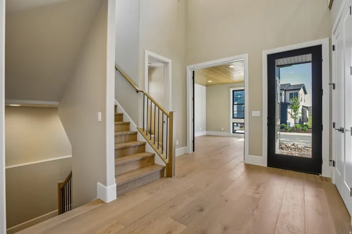 Entryway with wood-finish flooring, a contemporary staircase featuring wood handrails and black metal balusters, and a black-framed glass entry door