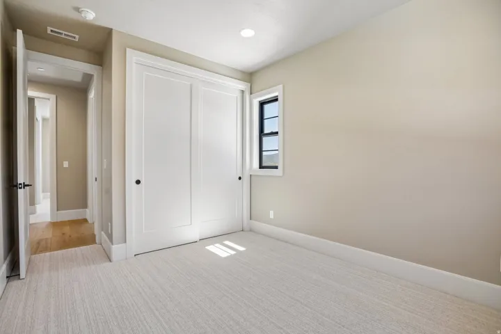 Carpeted room featuring a double-door closet, single pane window, and light neutral wall finishes