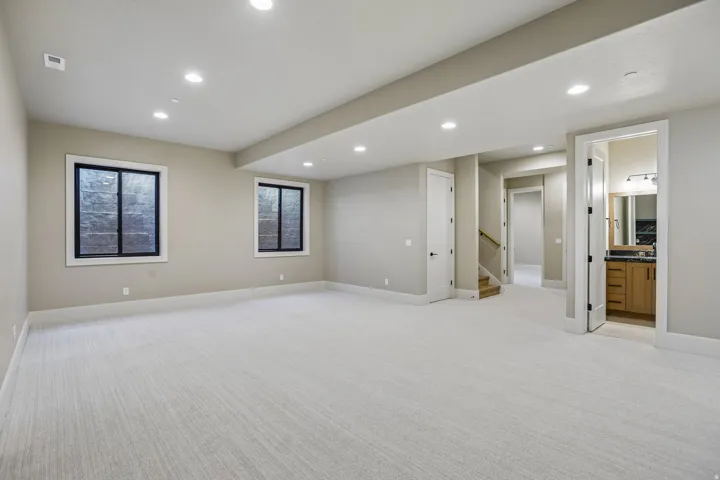 Spacious room with light-toned carpet flooring, recessed lighting, and two windows