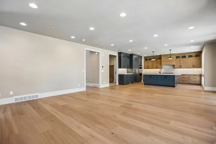Open-concept living space with light wood-finish flooring extending into the kitchen