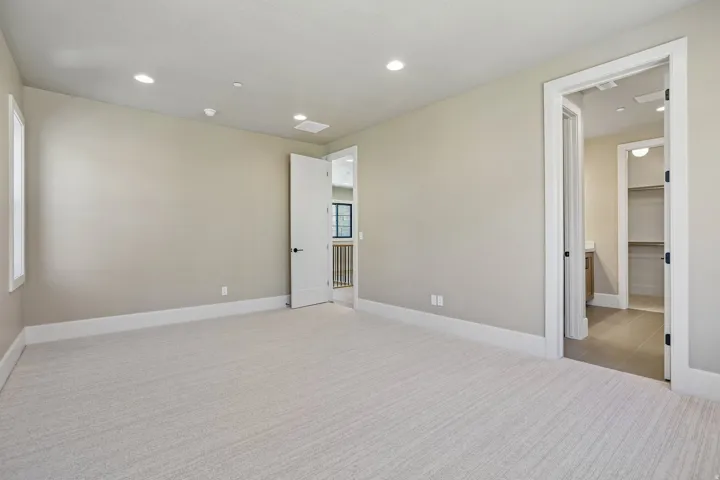 Spacious room featuring neutral carpeting, recessed lighting, and a window with white trim
