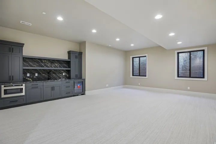 Spacious room featuring a built-in dark gray cabinetry unit with a black and gold patterned backsplash, integrated microwave, and beverage refrigerator