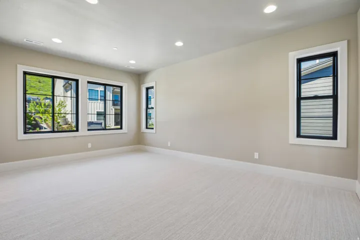 Spacious room featuring light-colored carpeting, neutral wall paint, and white trim