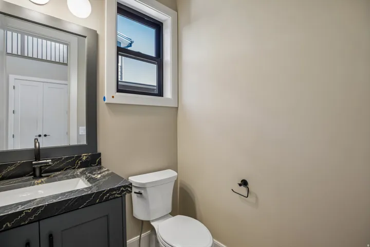 Bathroom featuring a dark vanity with a patterned countertop, an undermount sink, and a matte black faucet