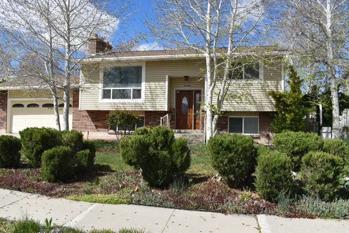 Split foyer home featuring brick siding, a garage, and a chimney