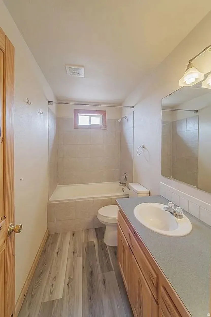 Bathroom featuring vanity, dark wood-style floors, and tiled shower / bath combo