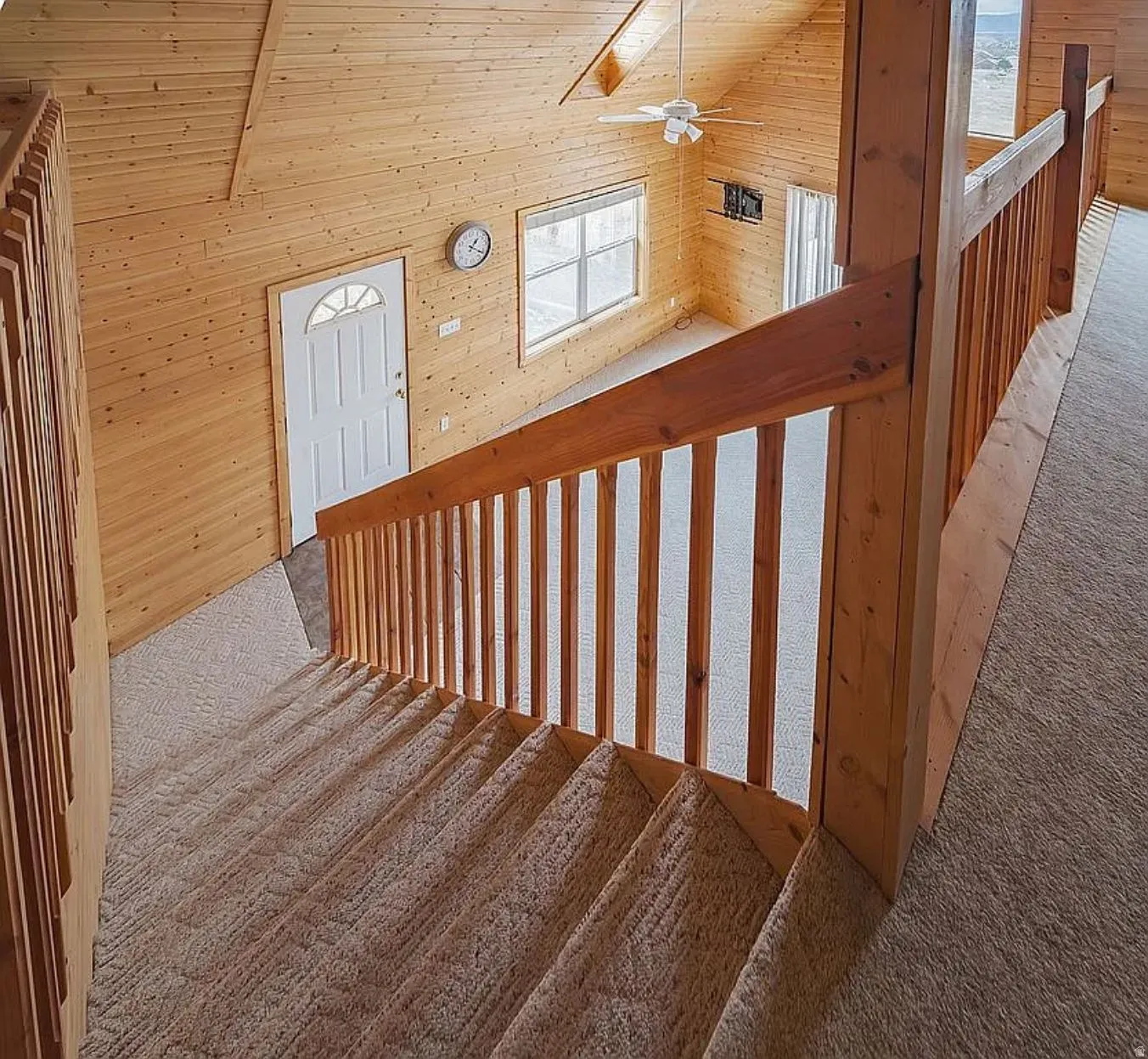 Stairs featuring wooden walls, carpet floors, a ceiling fan, and a high ceiling