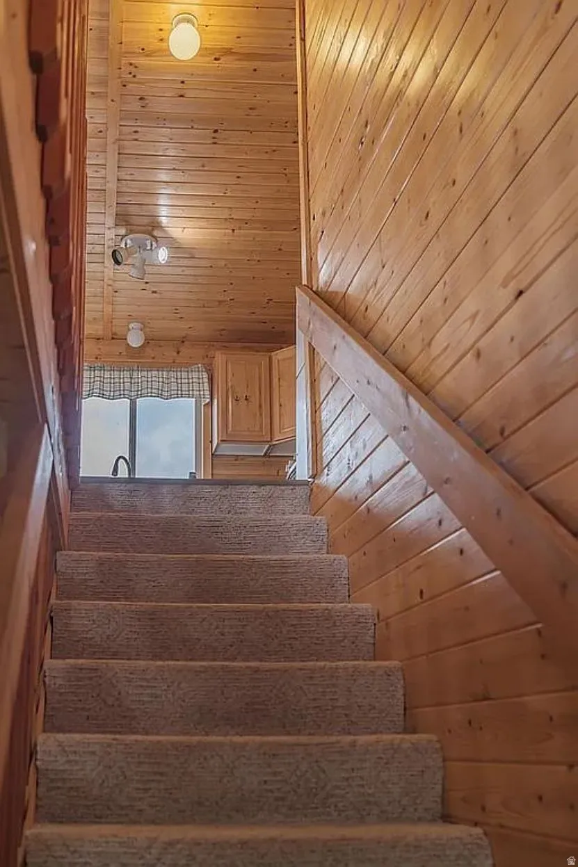 Staircase featuring wood walls and wooden ceiling
