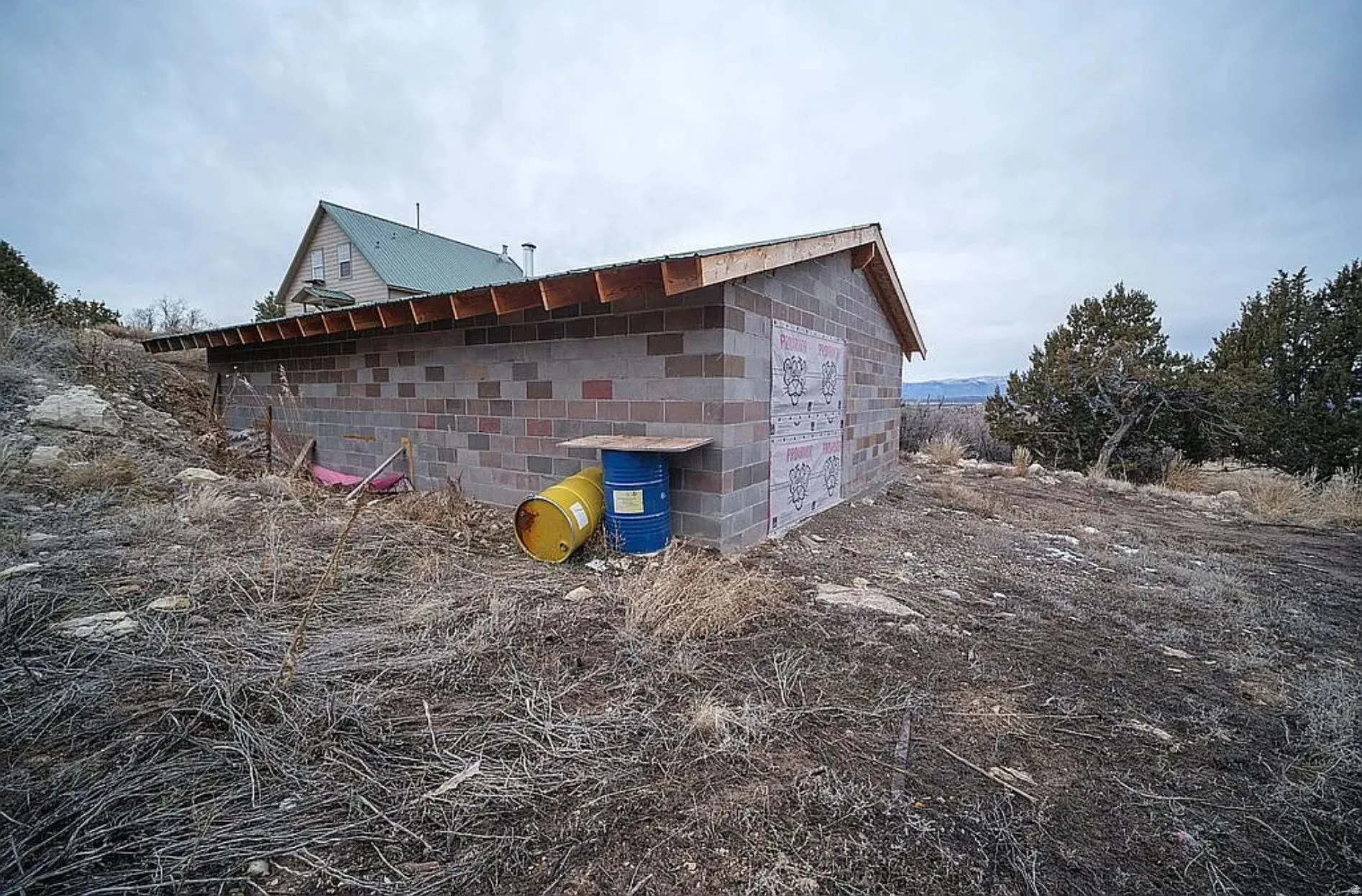 View of side of property featuring concrete block siding and an outbuilding