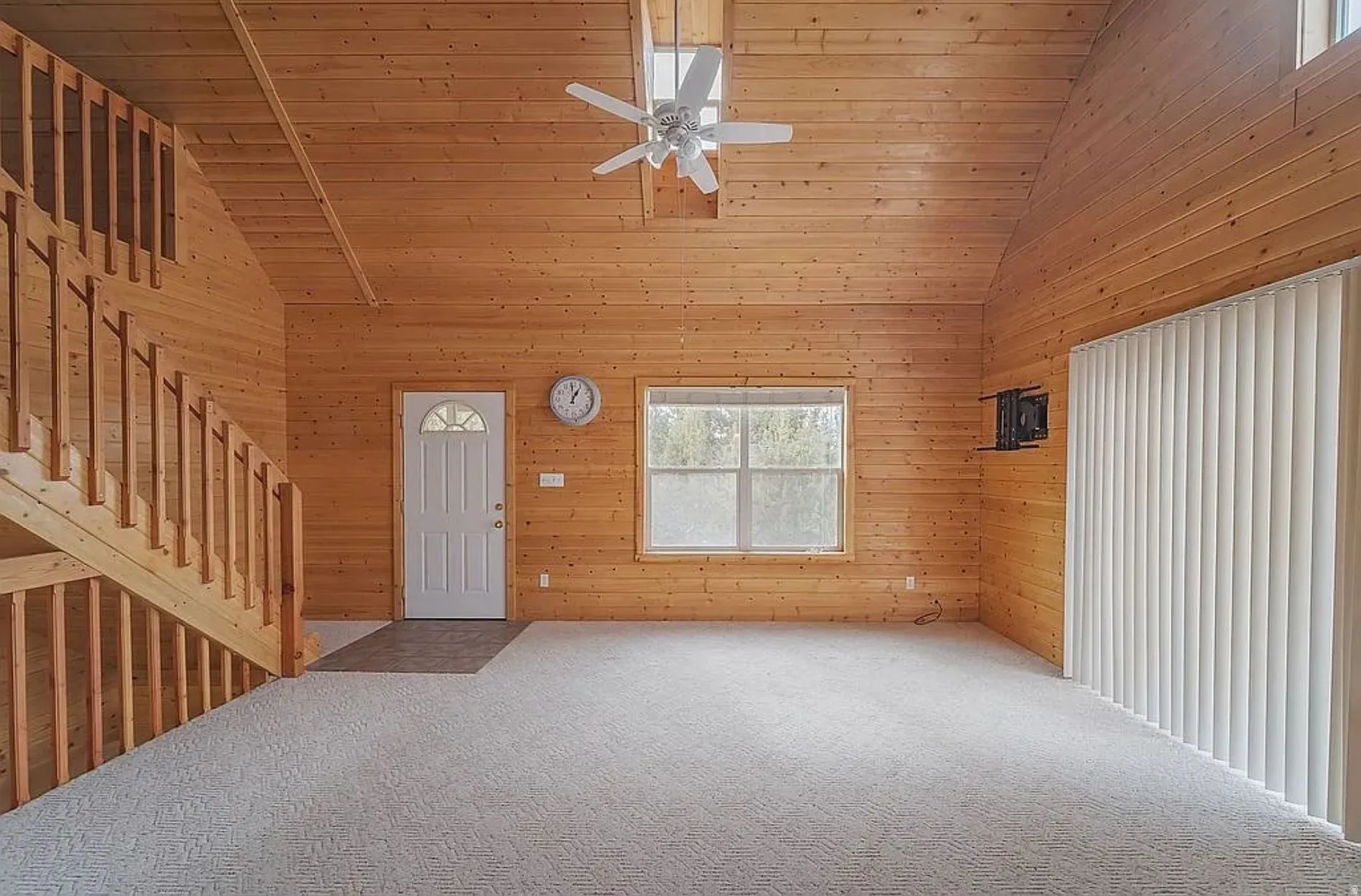 Foyer entrance featuring wooden walls, a ceiling fan, carpet, and a vaulted wooden ceiling