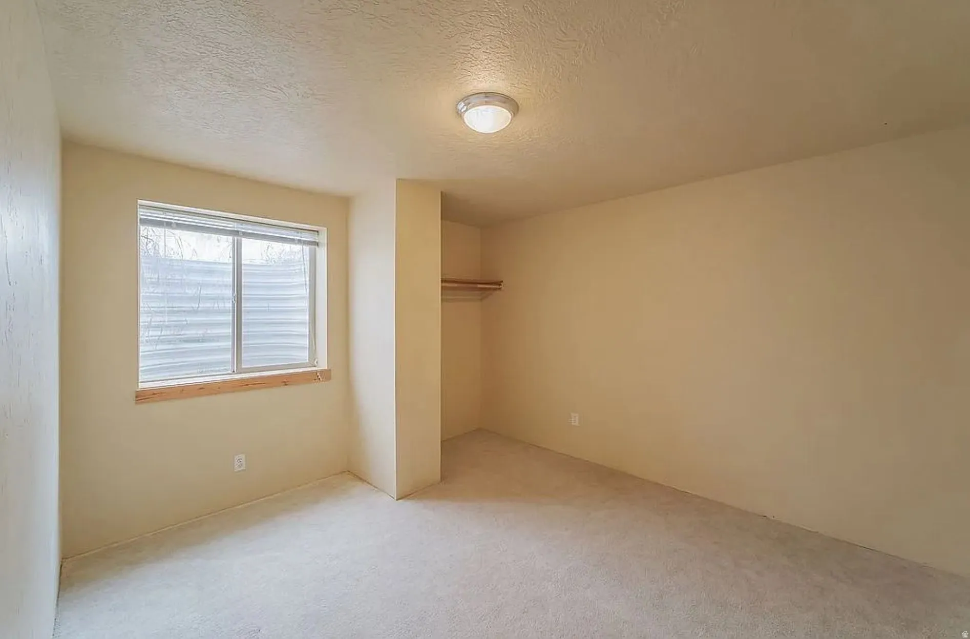 Unfurnished bedroom with a textured ceiling, a closet, and light colored carpet