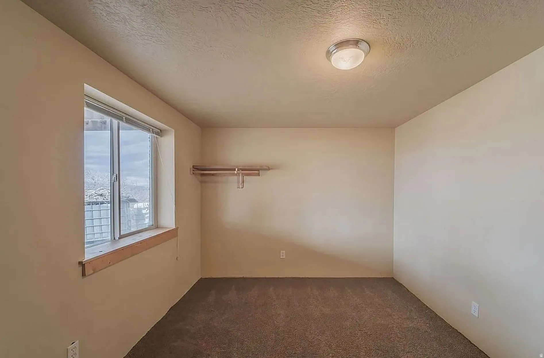 Empty room featuring dark colored carpet and a textured ceiling