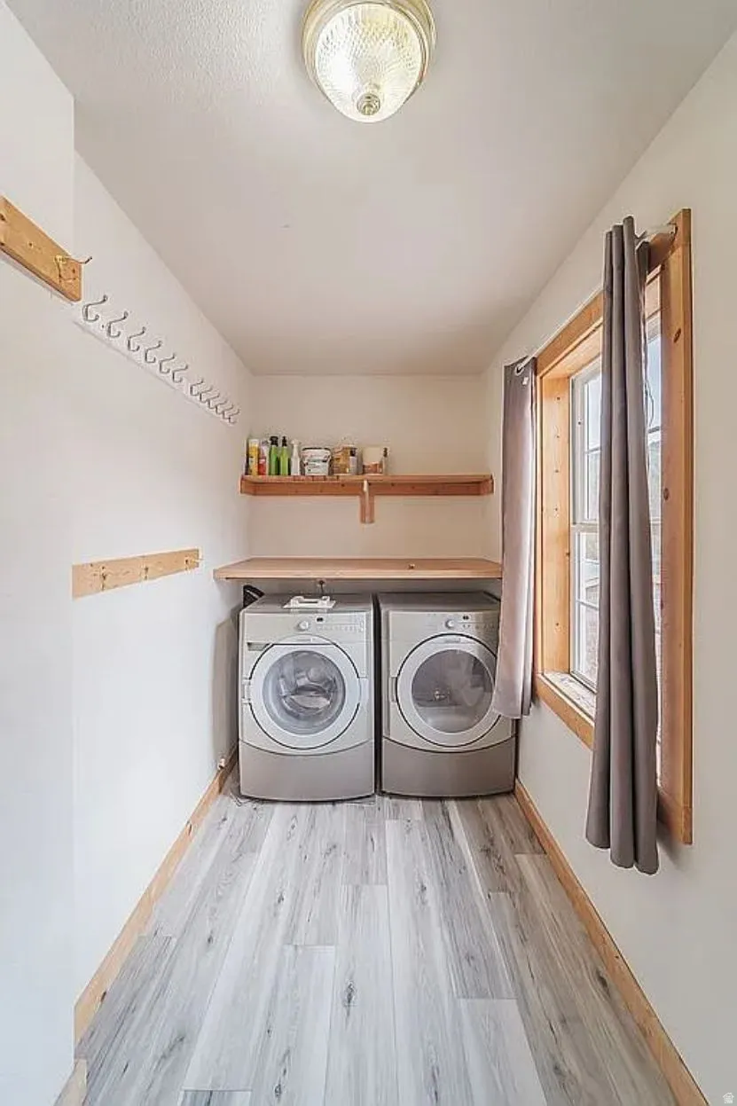 Laundry room with light wood-style floors and washing machine and dryer