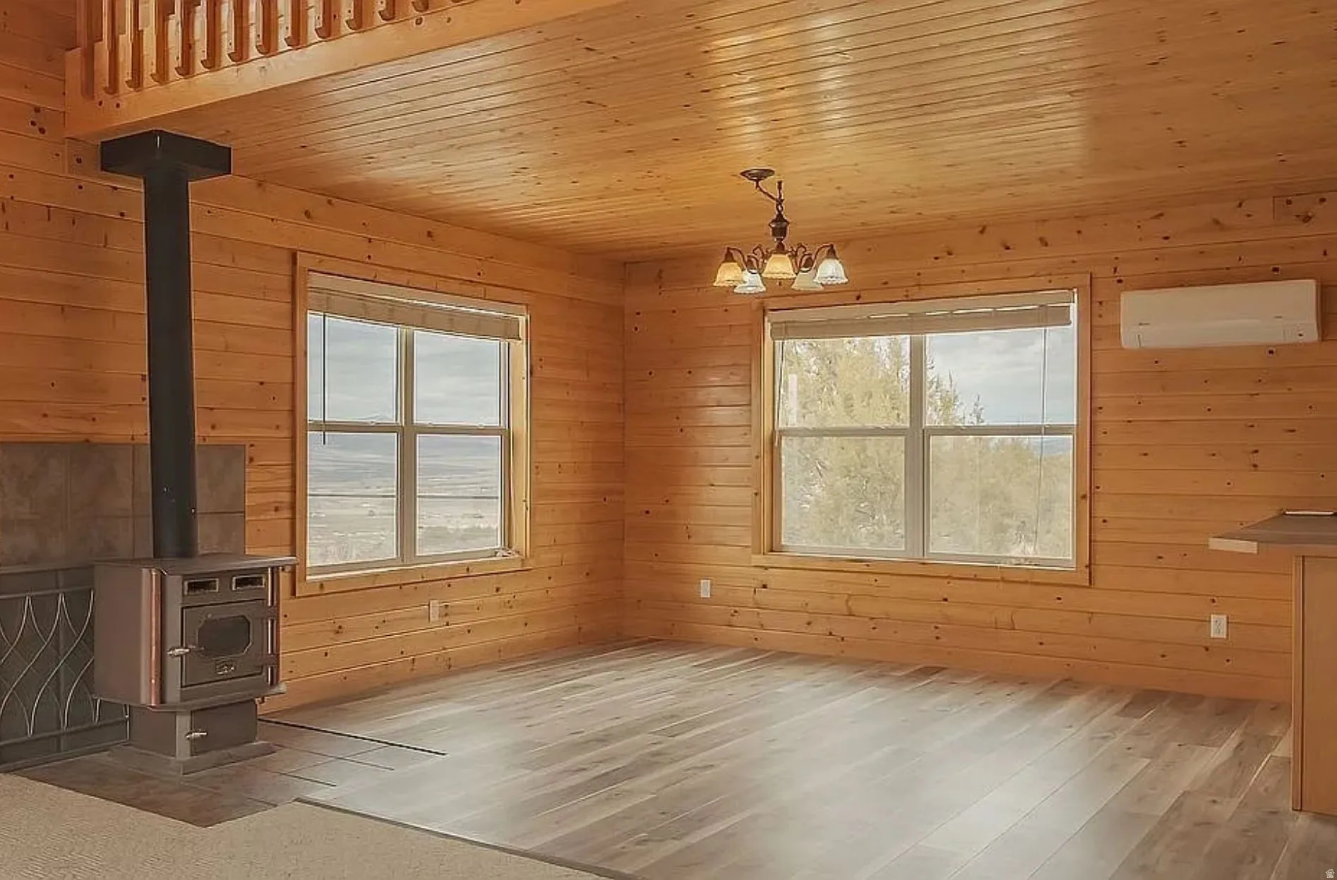 Unfurnished dining area with wooden walls, a wood stove, wood ceiling, light wood finished floors, and suspended lighting
