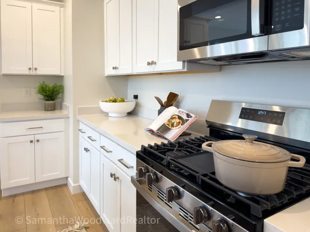 Kitchen with stainless steel appliances, white cabinetry, and light wood-style floors